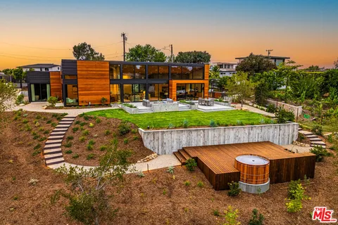 an outdoor sitting area with swimming pool and trees in the background