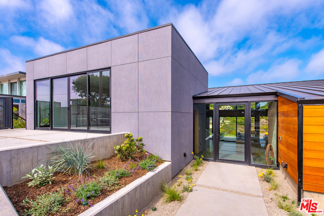 6756 Wandermere Road Malibu, CA 90265 - Photo 4 of 27 a front view of a house with a garden and glass windows