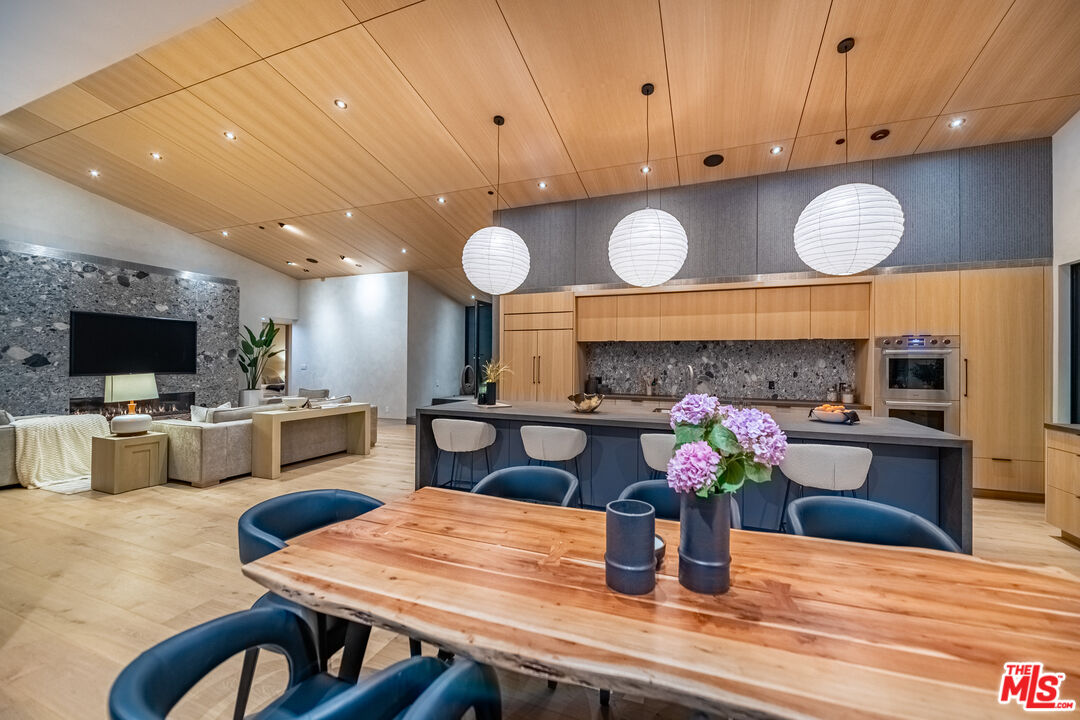 6756 Wandermere Road Malibu, CA 90265 - Photo 10 of 27 a kitchen with stainless steel appliances wooden floors dining table and chairs