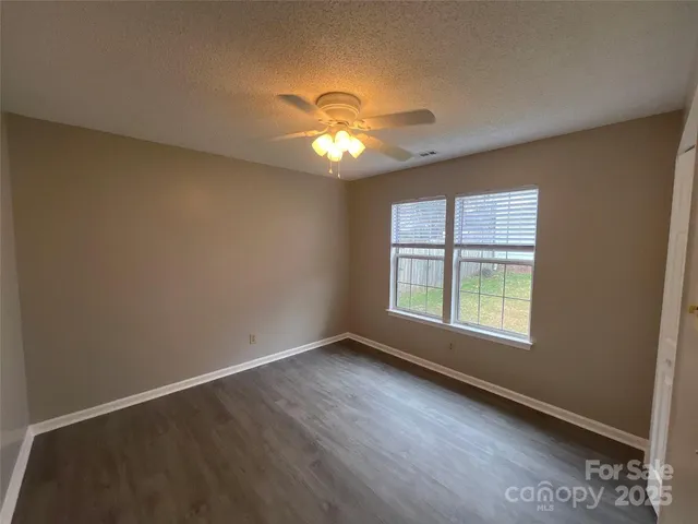 a view of an empty room with window and chandelier fan