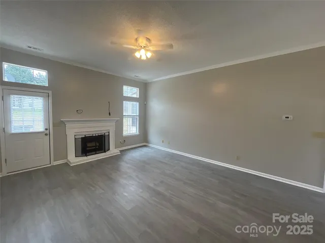 an empty room with wooden floor fireplace and windows