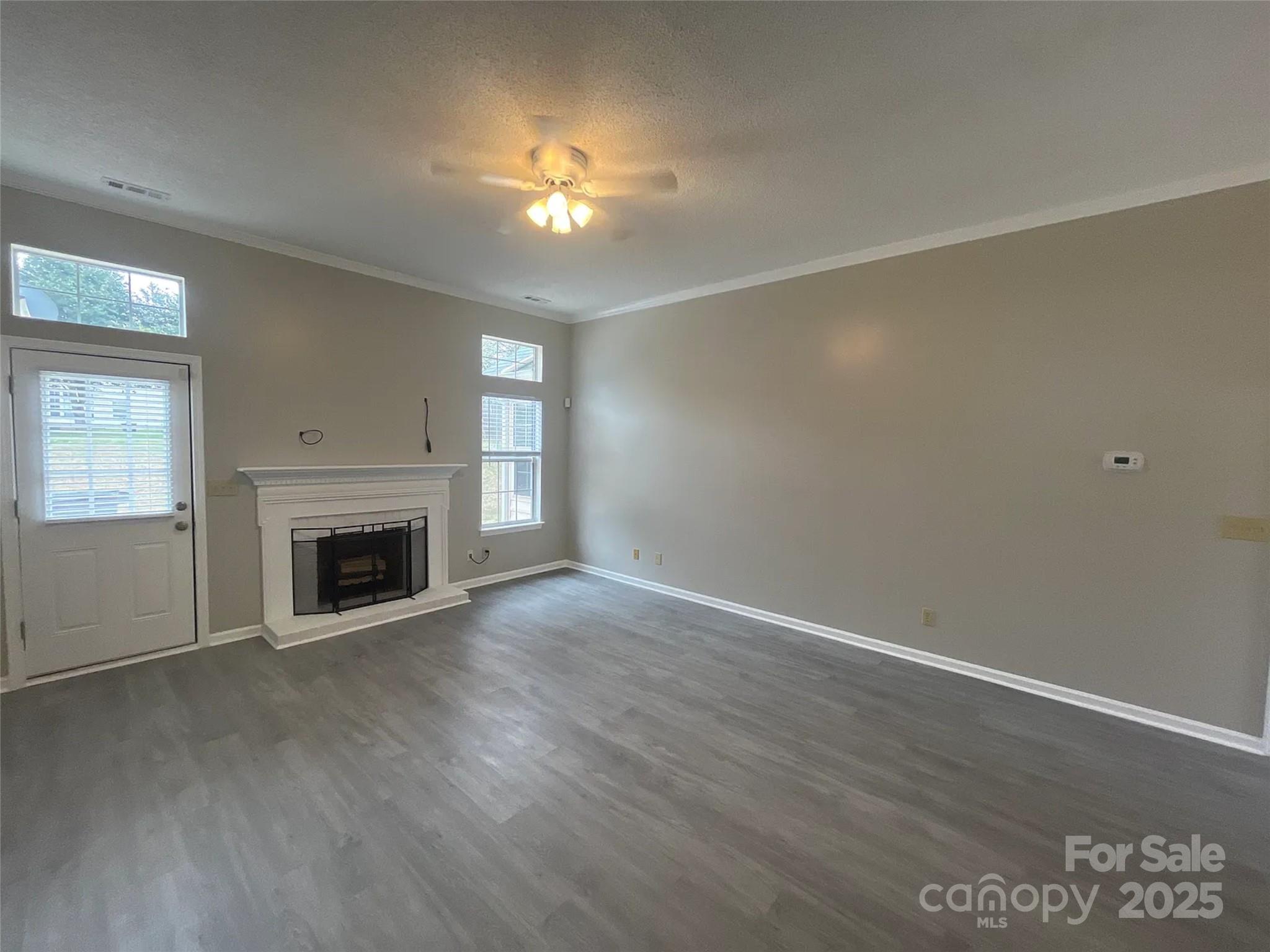 12042 Mallard Ridge Drive Charlotte, NC 28269 - Photo 3 of 19 an empty room with wooden floor fireplace and windows
