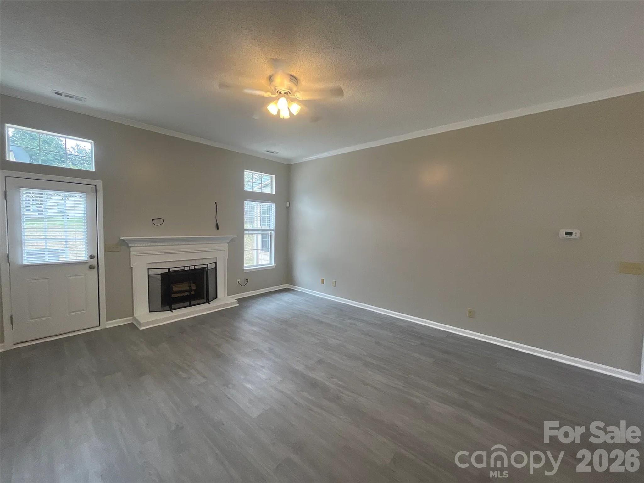 12042 Mallard Ridge Drive Charlotte, NC 28269 - Photo 3 of 20 an empty room with wooden floor fireplace and windows