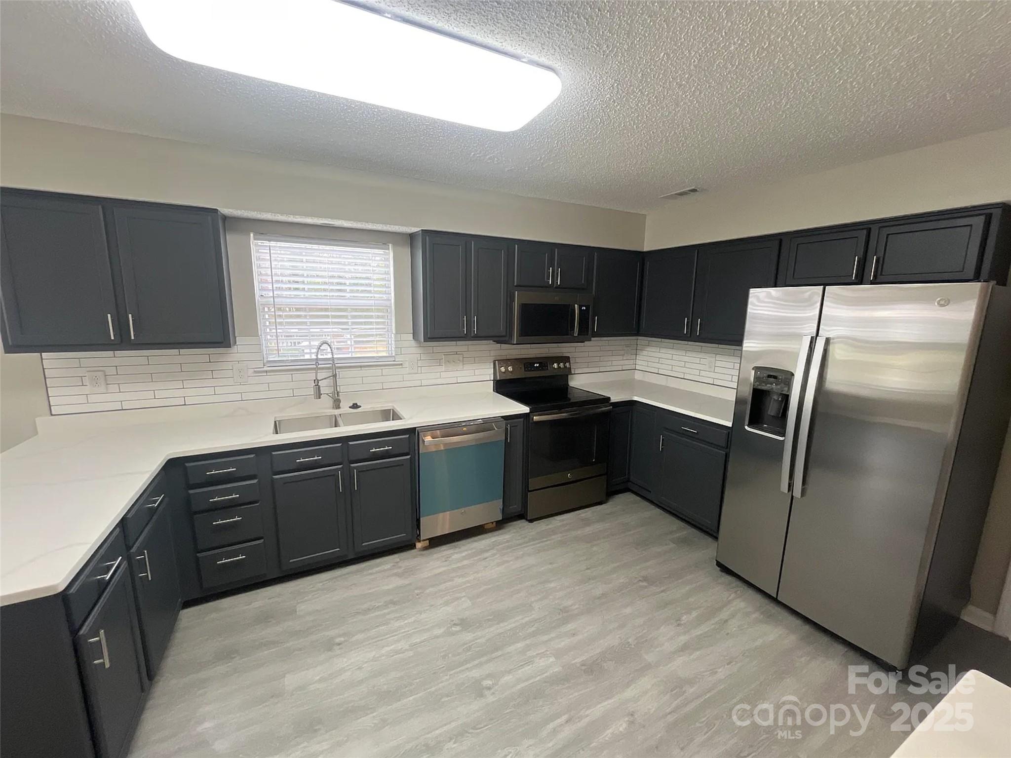 12042 Mallard Ridge Drive Charlotte, NC 28269 - Photo 5 of 19 a kitchen with a refrigerator sink and wooden cabinets