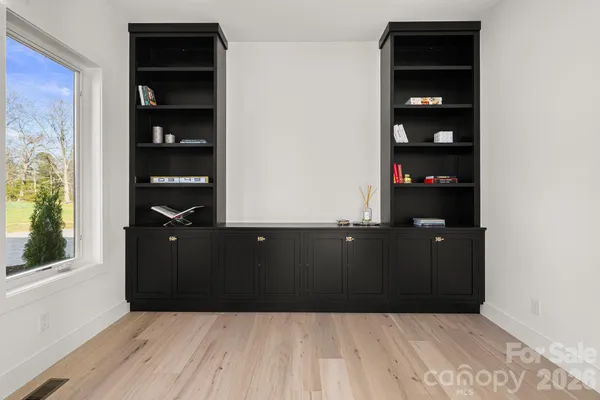 an empty room with wooden floor and windows