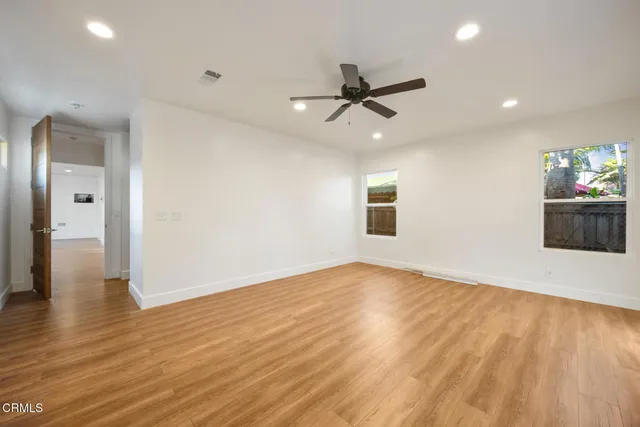 an empty room with wooden floor and windows