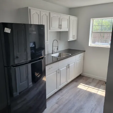 a kitchen with granite countertop a refrigerator a sink and wooden floors