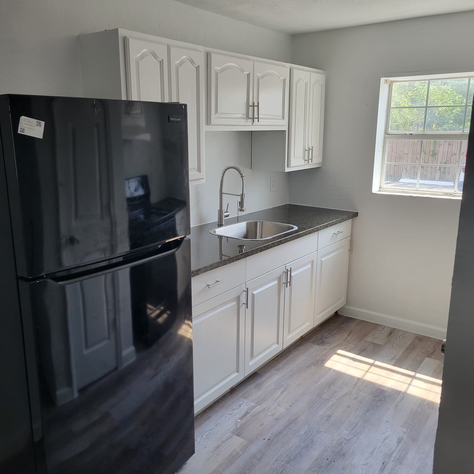 8605 Meta Street, Unit A Houston, TX 77022 - Photo 10 of 20 a kitchen with granite countertop a refrigerator a sink and wooden floors