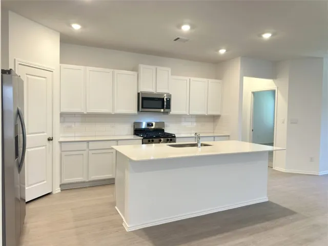 a kitchen with kitchen island a white counter top space cabinets and stainless steel appliances