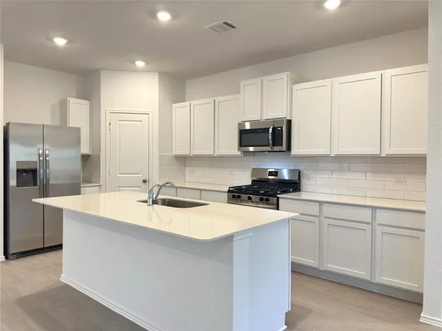 a kitchen with kitchen island a sink stainless steel appliances and cabinets