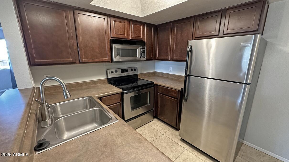 1720 East Thunderbird Road, Unit 2095 Phoenix, AZ 85022 - Photo 13 of 22 a kitchen with stainless steel appliances granite countertop a refrigerator a microwave a sink and cabinets