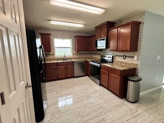 a kitchen with stainless steel appliances granite countertop a sink stove and refrigerator