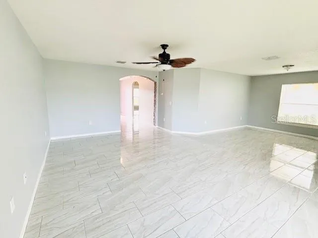 a view of empty room with window and ceiling fan