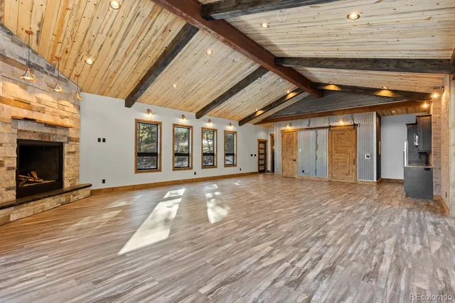 a view of an empty room with wooden floor and a fireplace