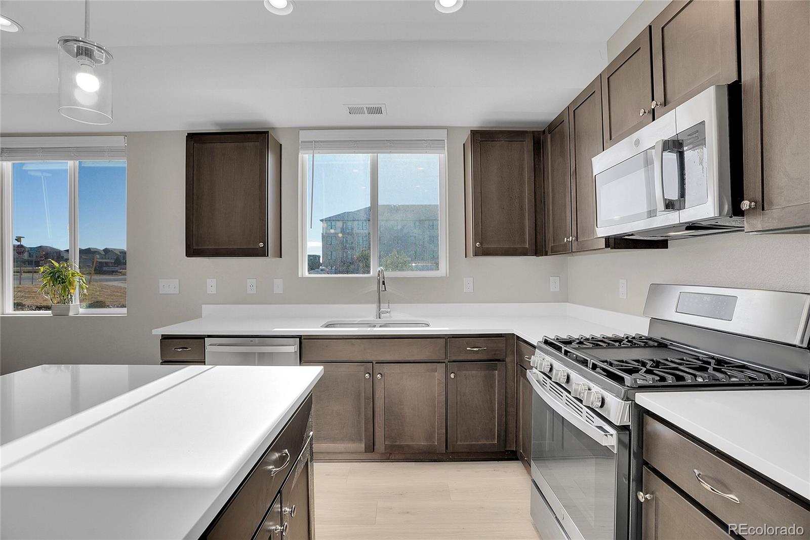 6419 North Dunkirk Street Denver, CO 80249 - Photo 13 of 31 a kitchen that has a sink and a stove in it