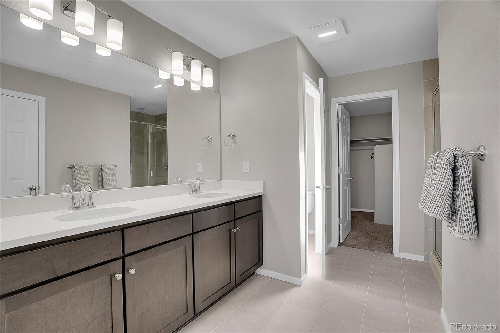 6419 North Dunkirk Street Denver, CO 80249 - Photo 26 of 31 a bathroom with a double vanity sink and a mirror