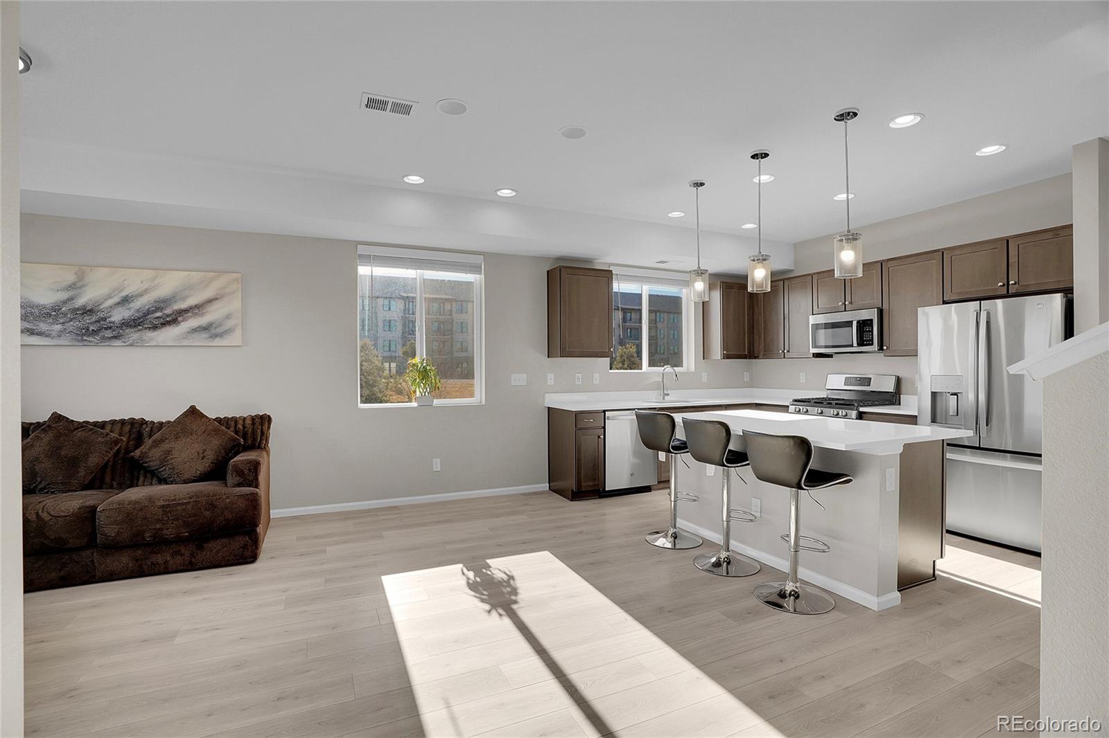 6419 North Dunkirk Street Denver, CO 80249 - Photo 5 of 31 a kitchen with stainless steel appliances kitchen island granite countertop a sink and a refrigerator