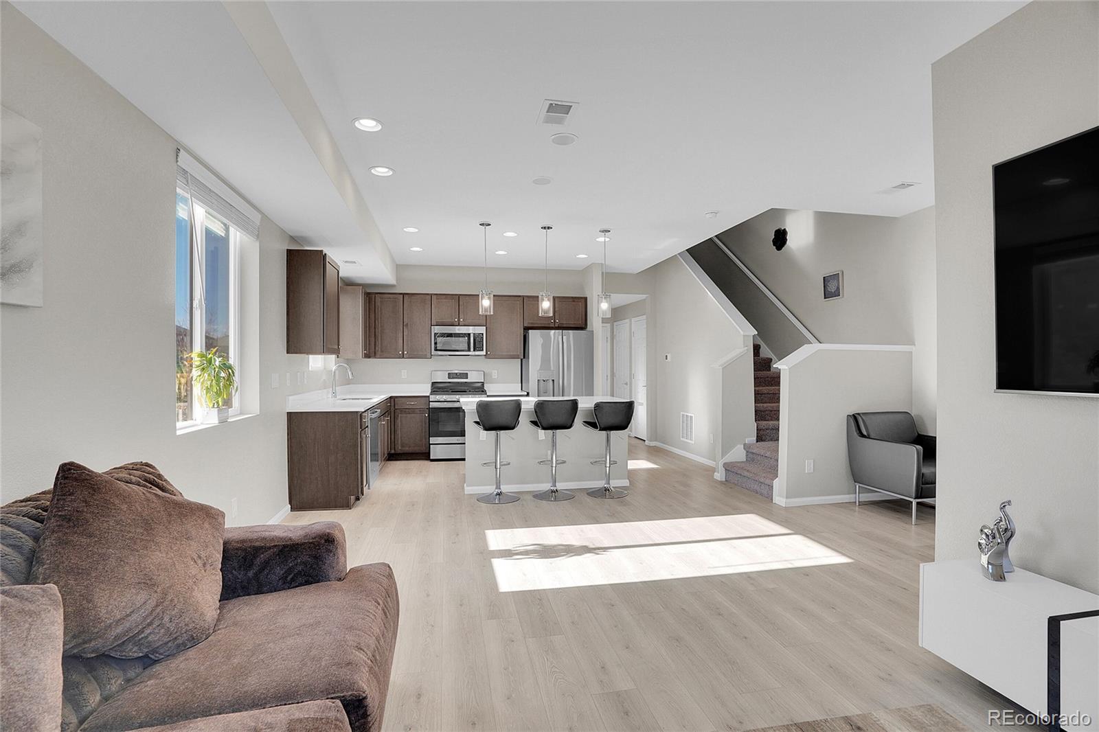 6419 North Dunkirk Street Denver, CO 80249 - Photo 9 of 31 a living room with stainless steel appliances kitchen island granite countertop a couch and a flat screen tv