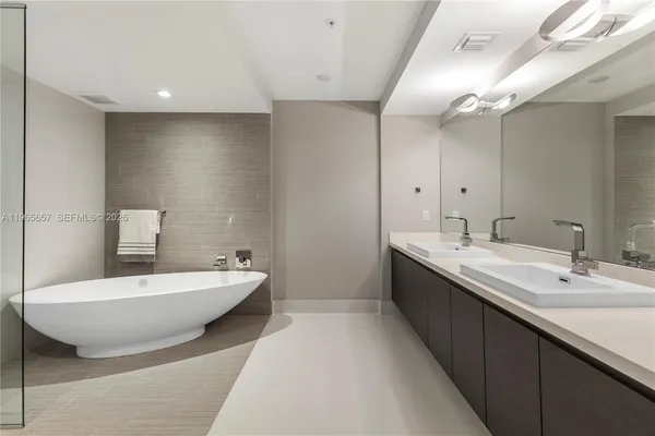 a spacious bathroom with a double vanity sink mirror and bathtub