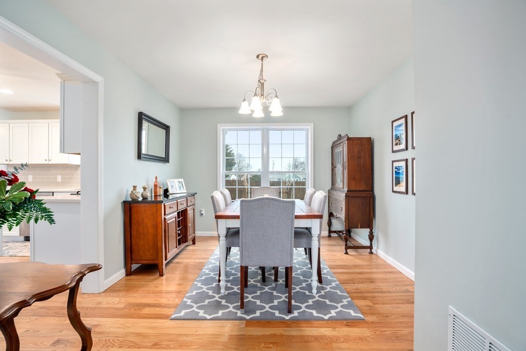 106 Colonial Road Marshfield, MA 02050 - Photo 10 of 42 a dining room with wooden floor a chandelier a glass table and chairs