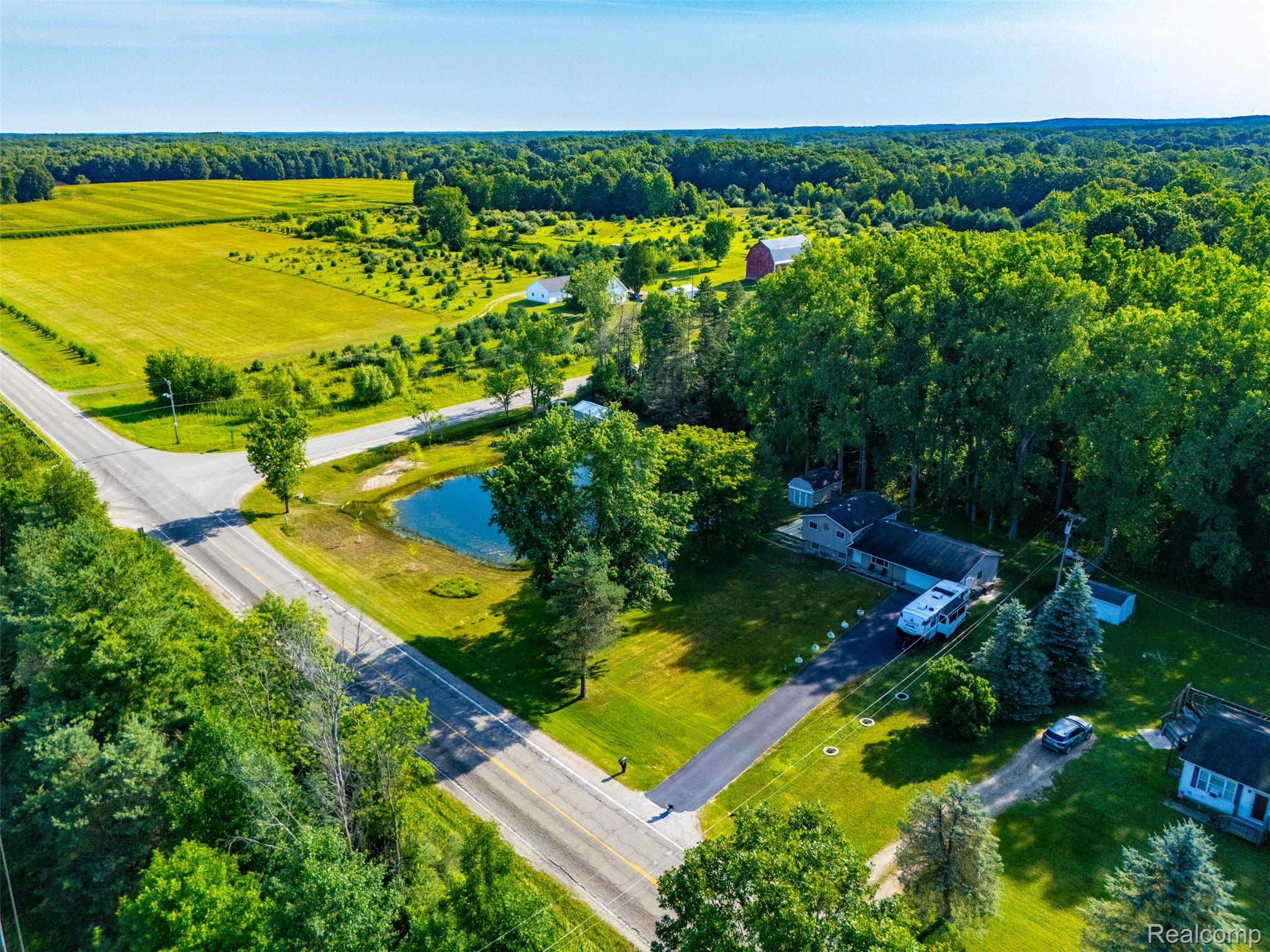 3744 Fish Lake Road Lapeer, MI 48446 - Photo 40 of 50 Property featuring a private pond, an extensive paved driveway, a single-story residence, mature trees, and a visible outbuilding