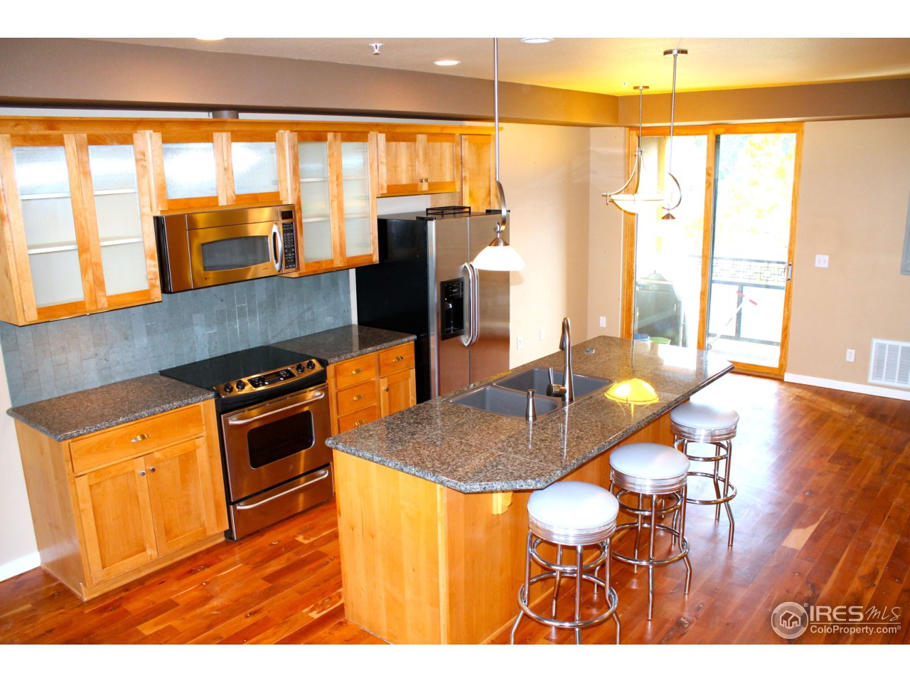 325 Cherry Street, Unit 210 Fort Collins, CO 80521 - Photo 3 of 13 a kitchen with stainless steel appliances granite countertop a stove a sink and a dining table with wooden floor