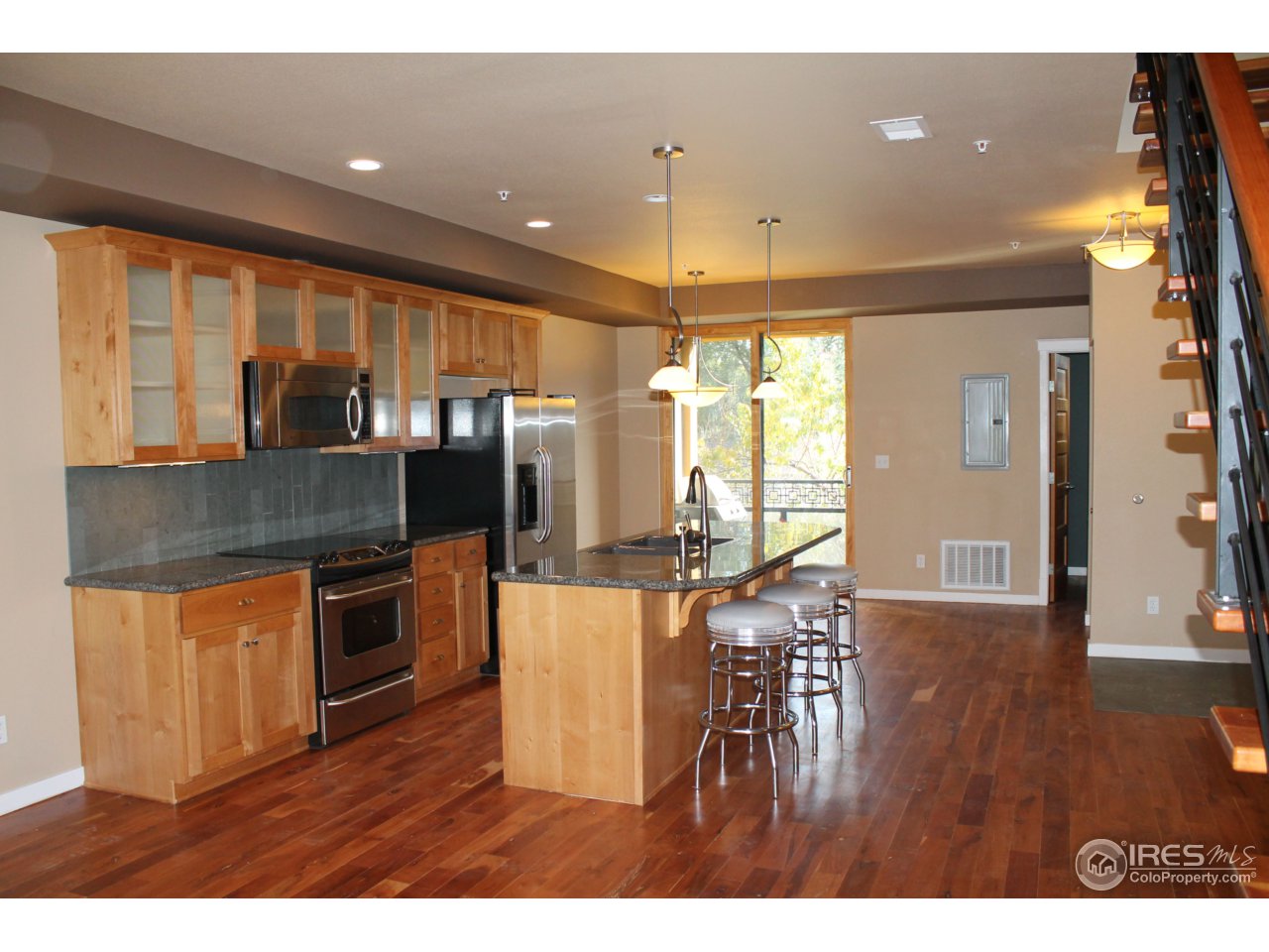 325 Cherry Street, Unit 210 Fort Collins, CO 80521 - Photo 7 of 13 a kitchen with stainless steel appliances granite countertop a refrigerator a sink dishwasher a stove and a dining table with wooden floor