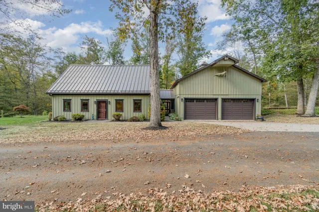 a front view of a house with a garden and trees
