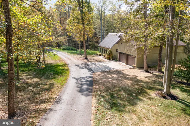 an aerial view of residential house with outdoor space and trees all around