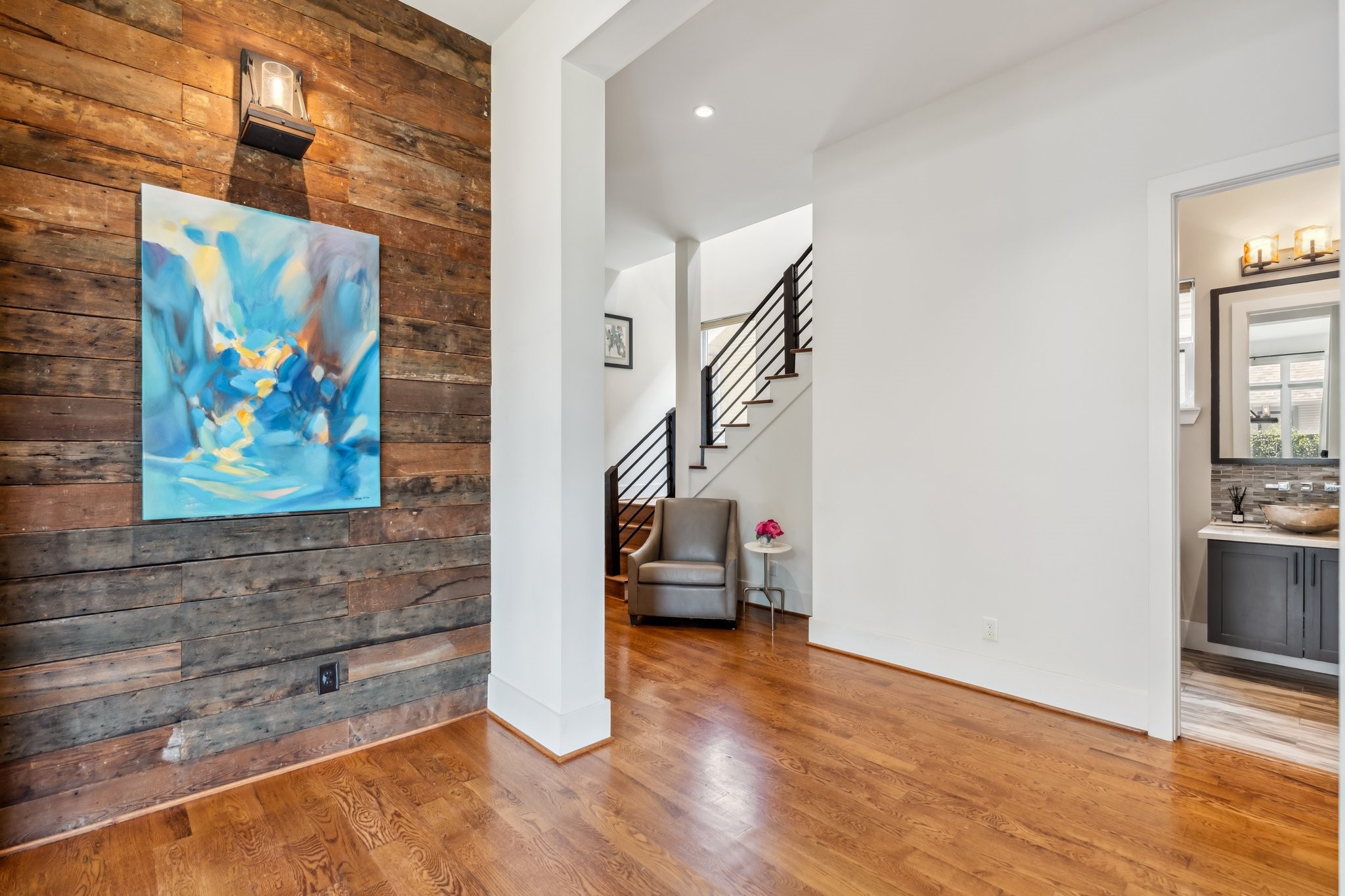 815 East 27th Street Houston, TX 77009 - Photo 4 of 44 As you enter this exquisite home, a striking wood-paneled accent wall with stylish sconce light greets you, setting the tone for the rest of the space. The entryway offers plenty of room for entry furniture & the perfect spot to showcase your favorite art pieces. A decorative chandelier adds a touch of elegance, while a convenient storage/coat closet keeps things organized. Enjoy views of the beautifully designed staircase with iron railings.