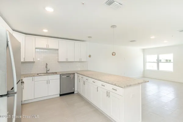 a kitchen with granite countertop a sink and white cabinets