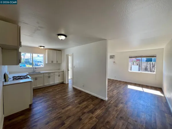a kitchen with a wooden floor a sink stainless steel appliances and cabinets