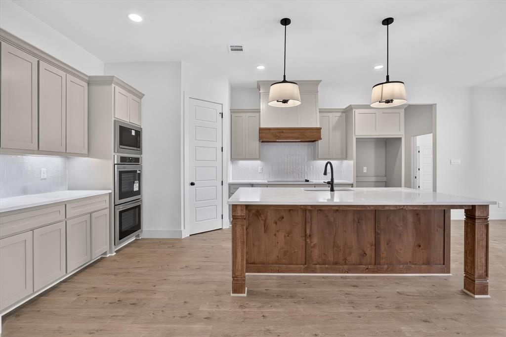 471 Red Bird Drive Springtown, TX 76082 - Photo 10 of 35 Expansive kitchen featuring a large wood-finish island with a light-toned countertop, complete with an undermount sink and matte black faucet