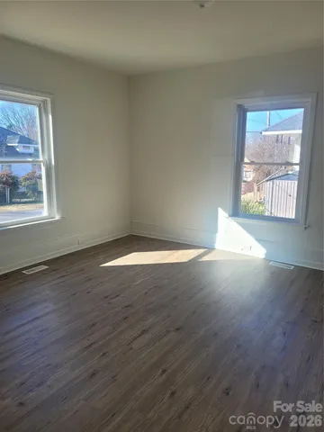 a view of a big room with wooden floor and windows