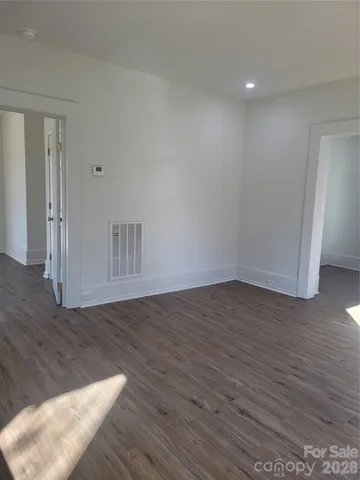 a view of an empty room with wooden floor and closet