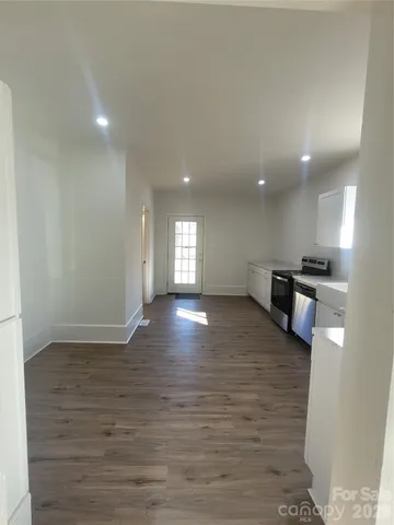 a view of empty room with kitchen and window