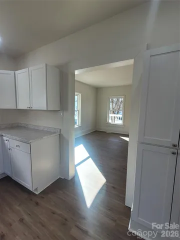 a view of an empty room with window and wooden floor