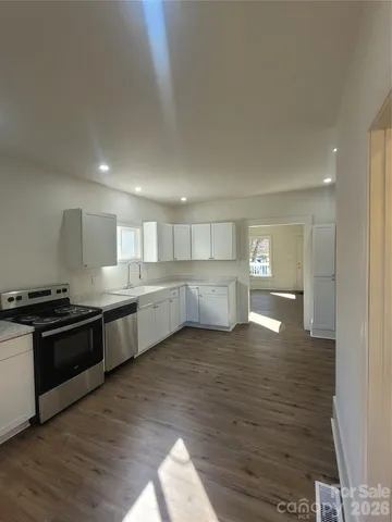 a large kitchen with wooden floors and stainless steel appliances
