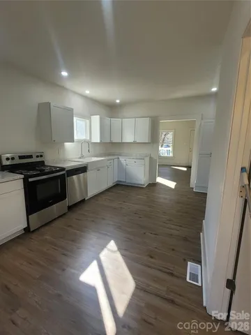 a large kitchen with wooden floors and stainless steel appliances