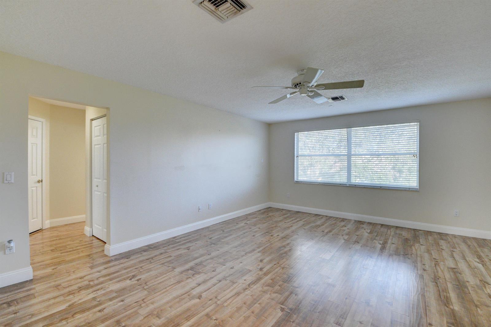 12920 Hyland Circle Boca Raton, FL 33428 - Photo 13 of 31 an empty room with wooden floor chandelier fan and windows