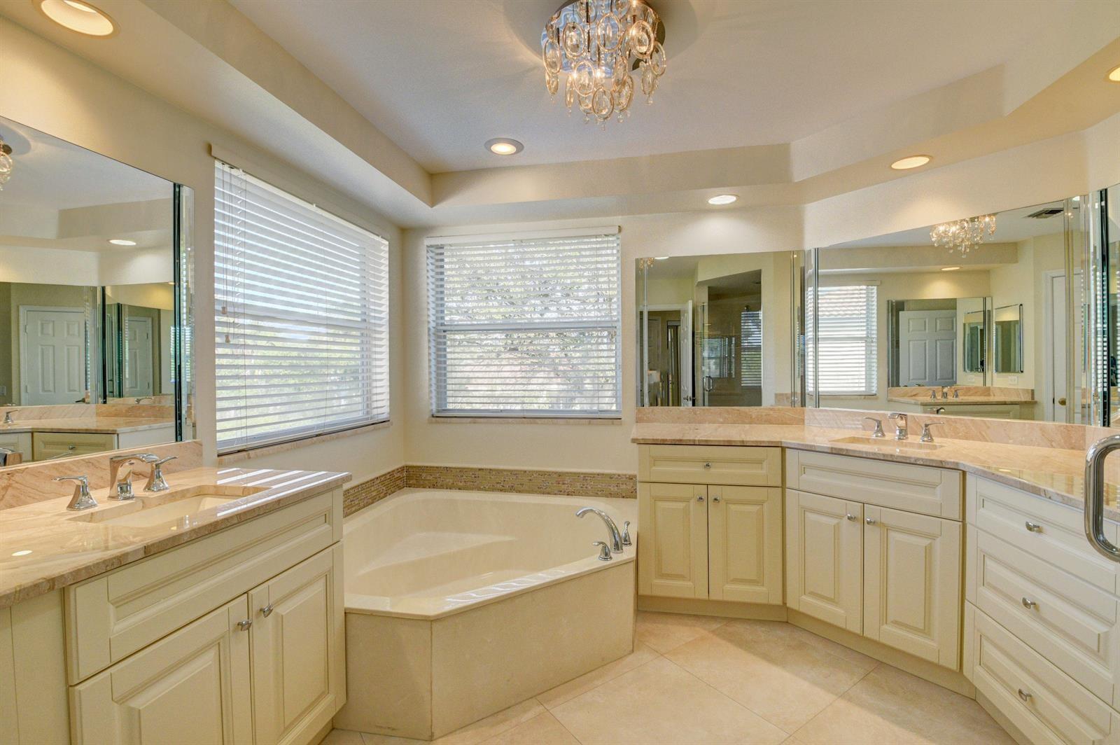12920 Hyland Circle Boca Raton, FL 33428 - Photo 14 of 31 a bathroom with a granite countertop sink a large mirror a bathtub and next to a window