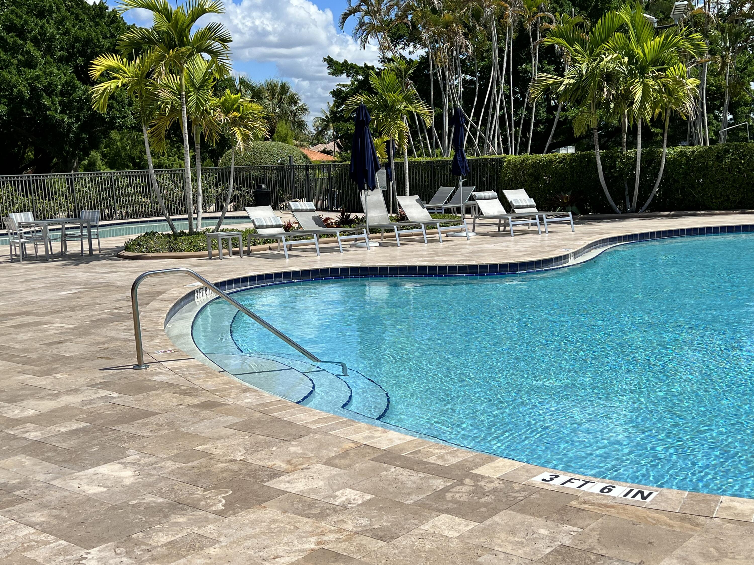 12920 Hyland Circle Boca Raton, FL 33428 - Photo 25 of 31 a view of a swimming pool with a lawn chairs under palm trees