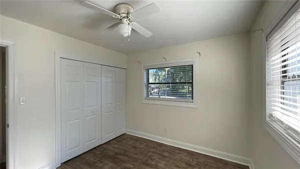 an empty room with windows and fan