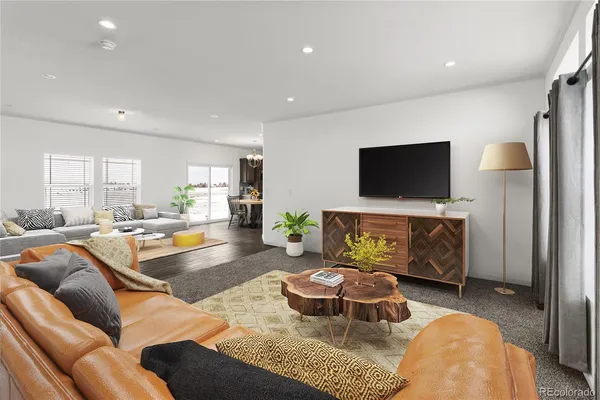 a living room with furniture a flat screen tv and kitchen view