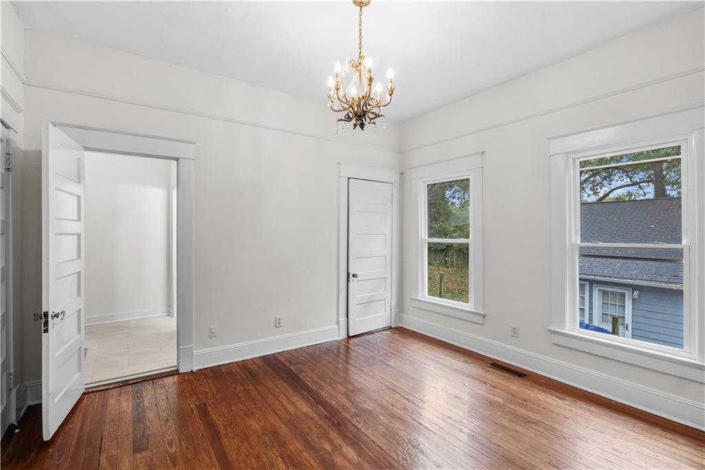 1440 Everhart Street Southwest Atlanta, GA 30310 - Photo 18 of 27 an empty room with wooden floor chandelier and windows