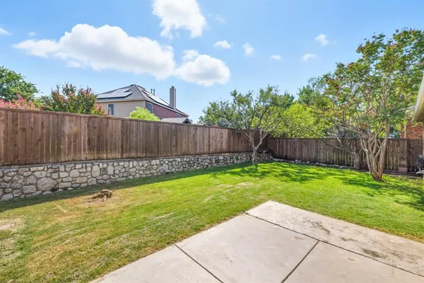 a view of a backyard with a garden and wooden fence