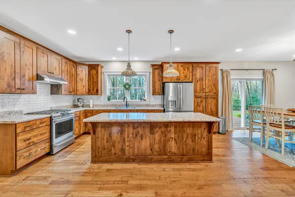 a large kitchen with stainless steel appliances granite countertop a stove a sink dishwasher a microwave oven and a dining table with wooden cabinet