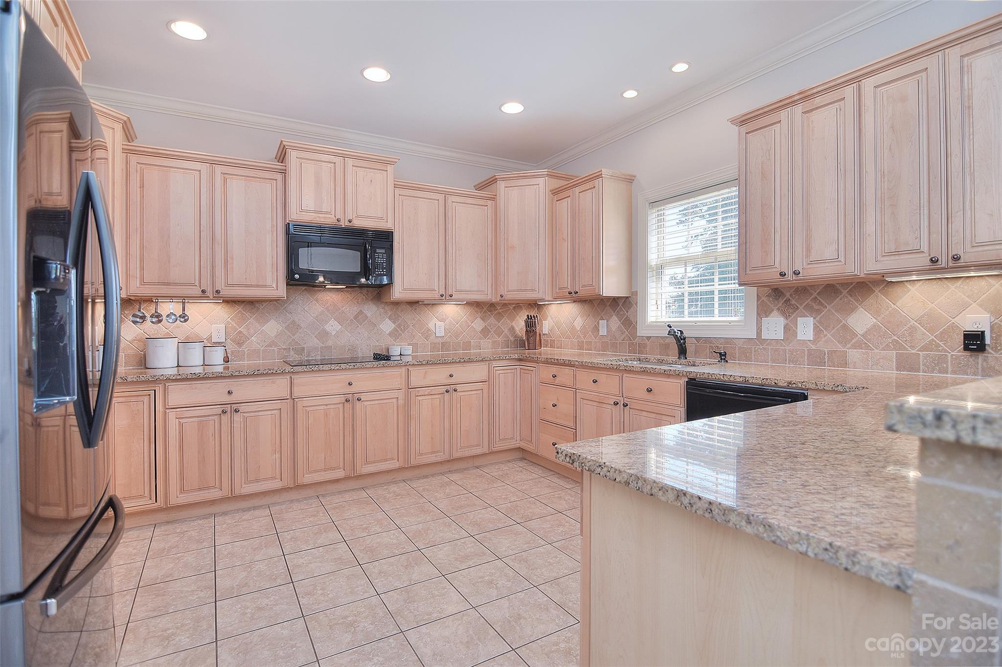 4913 Campobello Drive Monroe, NC 28110 - Photo 13 of 46 a kitchen with stainless steel appliances granite countertop a sink a stove a refrigerator a window and white cabinets