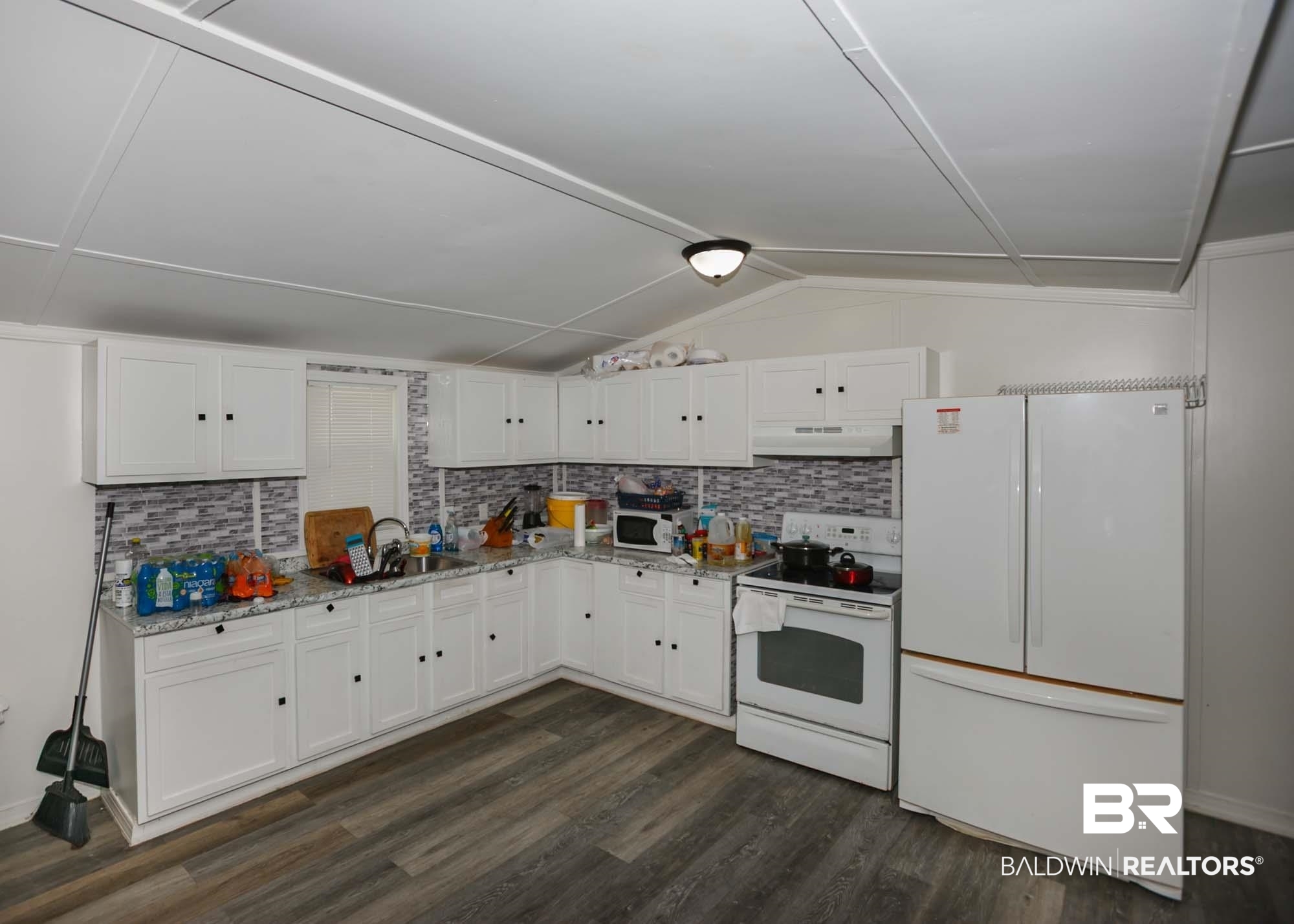 11998 Workman Avenue Foley, AL 36535 - Photo 7 of 59 Kitchen featuring white appliances, white cabinets, decorative backsplash, dark wood-type flooring, and vaulted ceiling