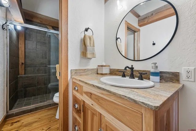 a bathroom with a granite countertop sink a mirror and a shower